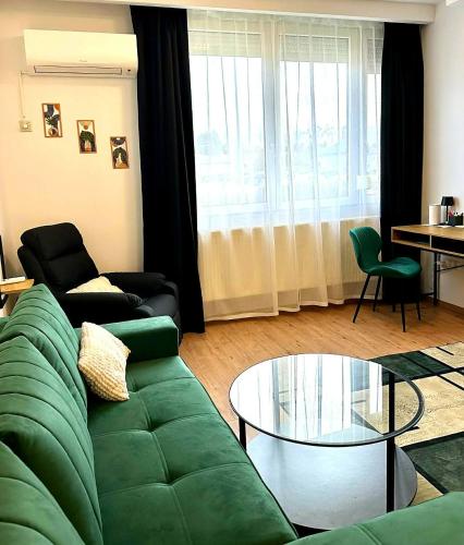 a living room with a green couch and a glass table at VestaLak in Tata