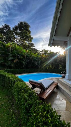 a swimming pool with a bench next to a house at Caribbean Hill Villas in Cocles