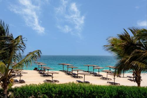 a beach with chairs and umbrellas and the ocean at Occidental Boa Vista Beach in Rabil