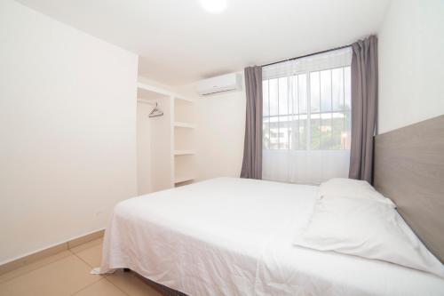 a bedroom with a white bed and a window at condominio los mangos in Santa Cruz Huatulco