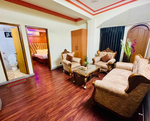 a living room with a couch and chairs and a bed at Hotel Rosewood Uttara in Kāmarpāra