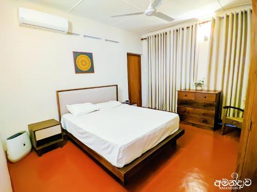 a bedroom with a white bed and a dresser in it at Amandawa Eco in Gampaha