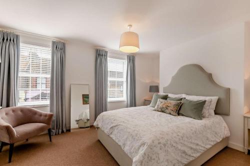 a bedroom with a bed and a chair and windows at 4 Bed in Walmer oc-c29264 in Deal