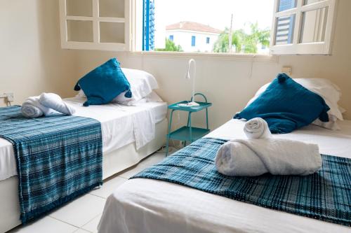 two beds in a room with blue pillows and towels at Spitaki by the Sea in Paralimni