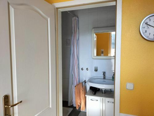 a bathroom with a sink and a clock on the wall at Eulennest-lu in Ludwigshafen am Rhein