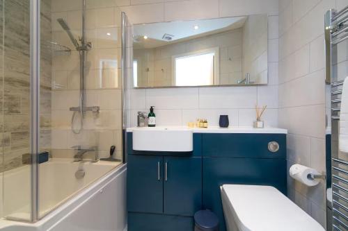 a bathroom with a blue sink and a shower at Modern Town House Bangor City Centre in Bangor