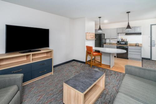 a living room with a flat screen tv and a kitchen at Candlewood Suites Loveland by IHG in Loveland