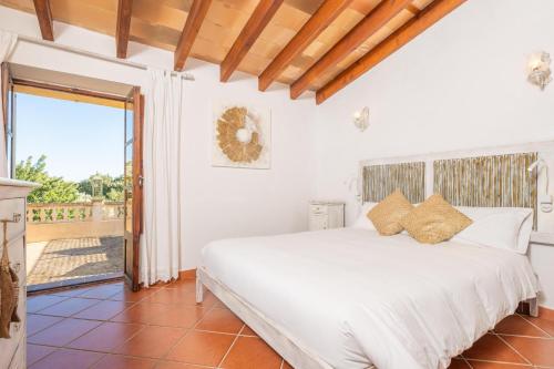 a bedroom with a white bed and a balcony at Es Raco in Caimari