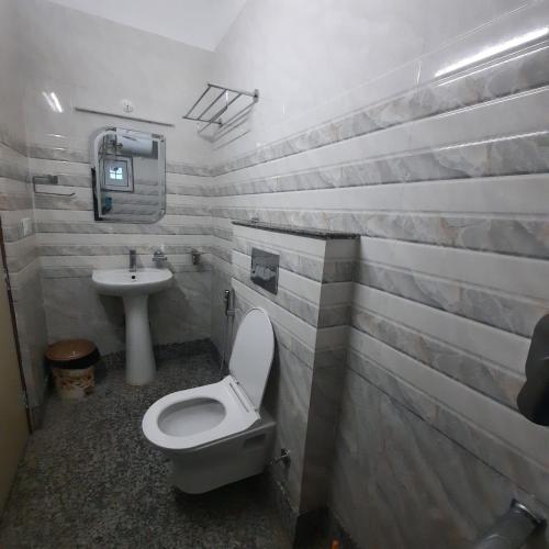 a bathroom with a toilet and a sink at Surakha INN LLP in Siliguri