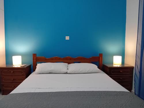 a blue bedroom with a bed with two nightstands and two lamps at White Villa in Xylokastro
