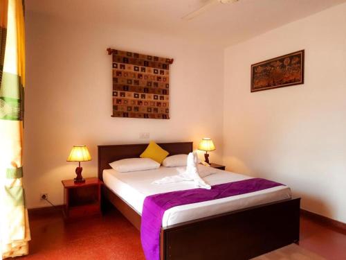 a bedroom with a bed with purple sheets and two lamps at Sunset Araliya by Diyakawa in Aluthgama