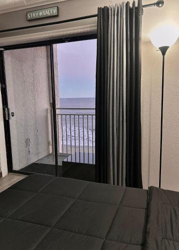 a bedroom with a view of the ocean from a balcony at Theo's Oceanfront Breeze in Myrtle Beach