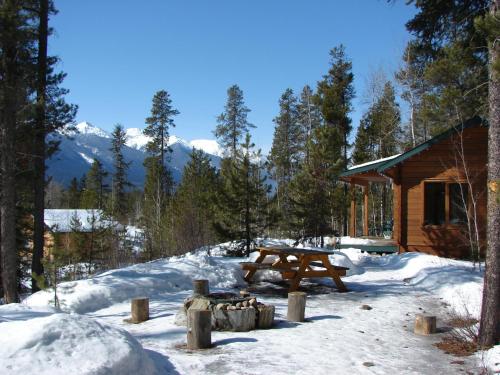 a picnic table in the snow in front of a cabin at Mica Mountain Lodge & Log Cabins in Tete Jaune Cache