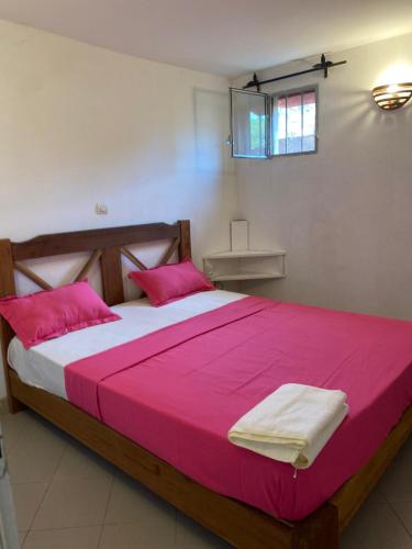 une chambre avec un grand lit et des oreillers roses dans l'établissement Chez Mathilde, à Cap Skirring