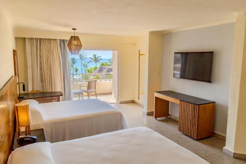 a hotel room with two beds and a television at Friendly Fun Vallarta Different Experiences - All Inclusive in Puerto Vallarta