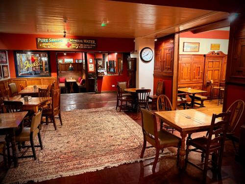 a restaurant with wooden tables and chairs and a clock at Swan Hotel Forton in Forton