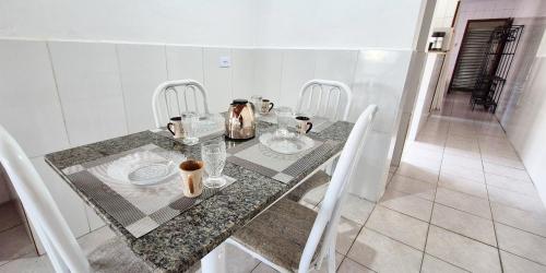 a dining table with white chairs and a table and a table and chairs at STO01 - Casa ampla em bairro tranquilo do Guarujá in Guarujá