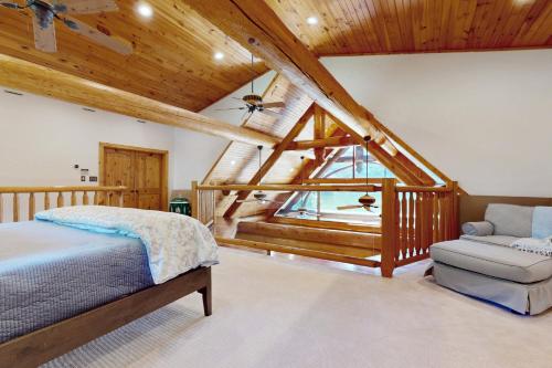 a bedroom with a bed and a chair in a attic at Hot Tub + Dock! Waterfront Norris Lake Log Home in Elm Springs