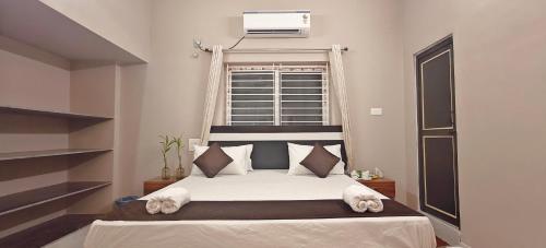 a bedroom with a bed with white sheets and a window at Sukra Residency in Valavanūr