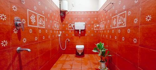 a red bathroom with a toilet and a sink at Sukra Residency in Valavanūr