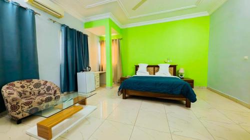 a bedroom with green walls and a bed and a chair at WELCOME LODGE in Ouagadougou