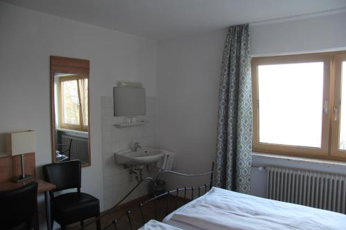 a bedroom with a bed and a sink and a window at Huberwirt am Kellerberg in Wasserburg am Inn