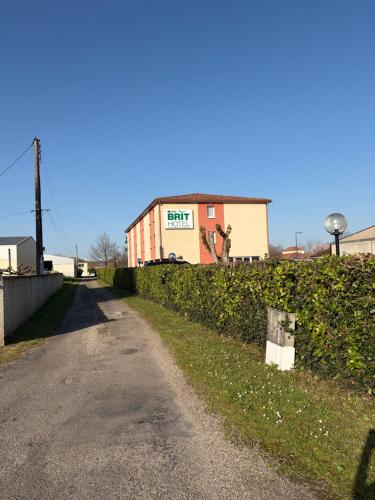 a road next to a hedge with a building in the background at Brit Hotel Confort Villeneuve Sur Lot in Bias