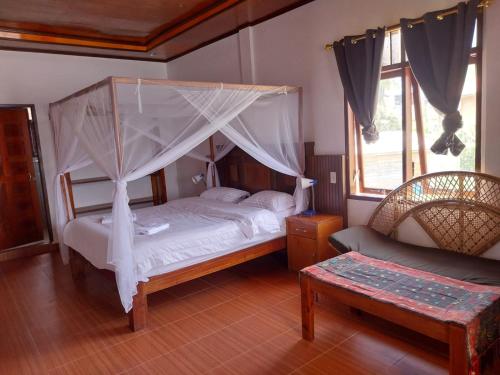 a bedroom with a canopy bed and a chair at Toba Sunset in Tuktuk Siadong