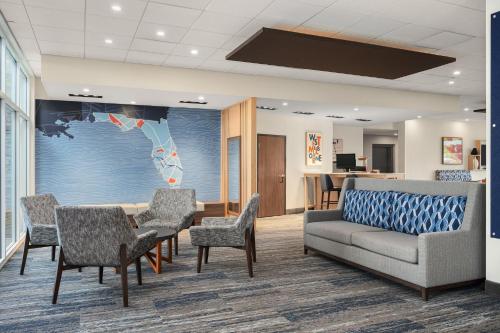 a waiting room with a couch and a table and chairs at Holiday Inn Express Melbourne West by IHG in Melbourne