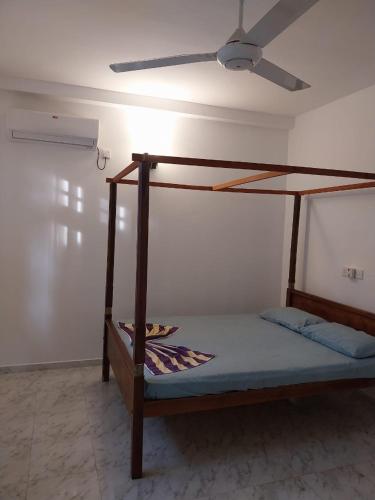 a bedroom with a wooden bed with a ceiling fan at Villa Anu in Hikkaduwa