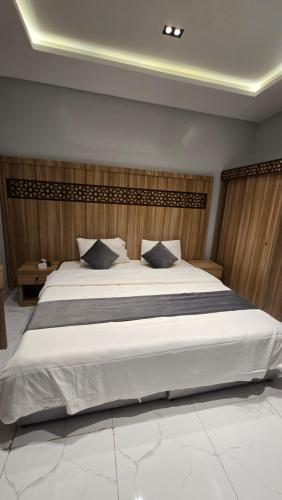 a bedroom with a large white bed with black pillows at شقق الدار in Jeddah