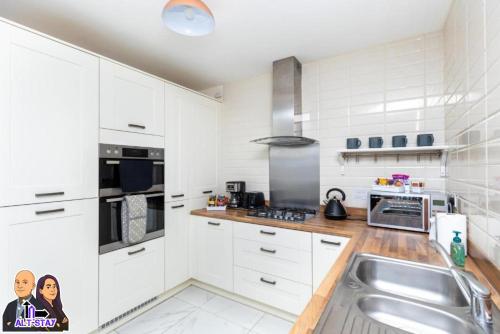 a kitchen with white cabinets and a stainless steel sink at Kirkstall by Alt-Stay Contractor Accommodation - 4 Bed Contractor Home With Parking, Wi-Fi & Full Kitchen - Ideal For Long stays in Wakefield