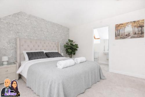 a white bedroom with a large bed with two towels at Kirkstall by Alt-Stay Contractor Accommodation - 4 Bed Contractor Home With Parking, Wi-Fi & Full Kitchen - Ideal For Long stays in Wakefield