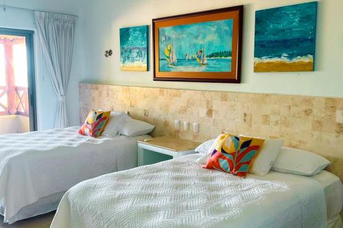a bedroom with two beds and paintings on the wall at Villa Arkoi in Uaymitun