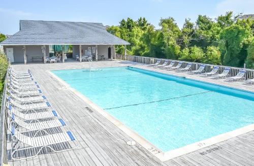 a large swimming pool with chairs and a house at Crow's Nest - Corolla, Crown Point, 150 Yds to Beach, Hot Tub, Community Pool, Pets OK in Corolla