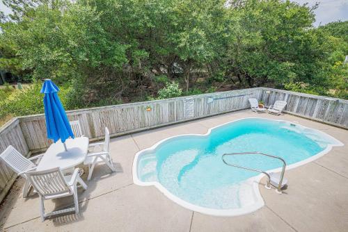 a swimming pool with chairs and an umbrella and a table and chairs at Beach Place - Corolla, Ocean Sands, 370 Yards to the Beach, Flex Stays, Pets OK, Pool! in Corolla
