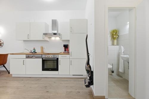 a white kitchen with a guitar leaning against the wall at Ferienwohnungen "Godewind", Appartements mit Balkon oder Terrasse in Zinnowitz