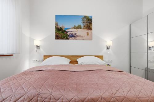 a bedroom with a large bed with a pink comforter at Ferienwohnungen "Godewind", Appartements mit Balkon oder Terrasse in Zinnowitz