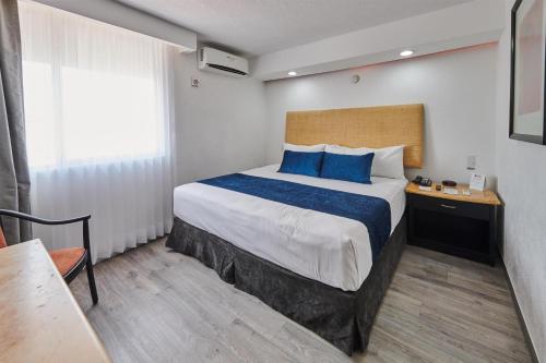 a bedroom with a large bed with blue pillows at Best Western Plus Gran Hotel Centro Historico in Guadalajara