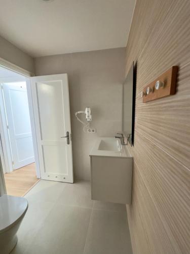 a bathroom with a white sink and a door at Bel Air Surf Escape in El Cotillo