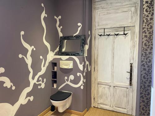 a bathroom with a toilet and a wall with a tree mural at Le Jardin de LaCoste in Narbonne