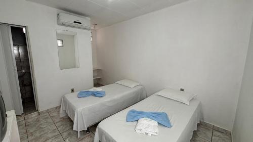 two beds in a small room with a mirror at Pousada Novo Millenium in Araripina