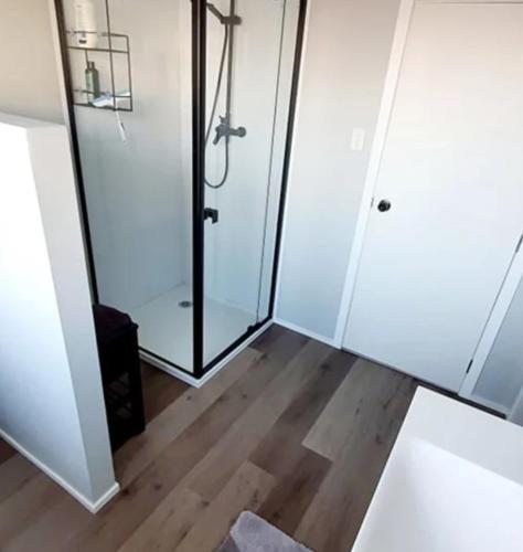 a bathroom with a glass shower and a wooden floor at B&B on Station in Paeroa