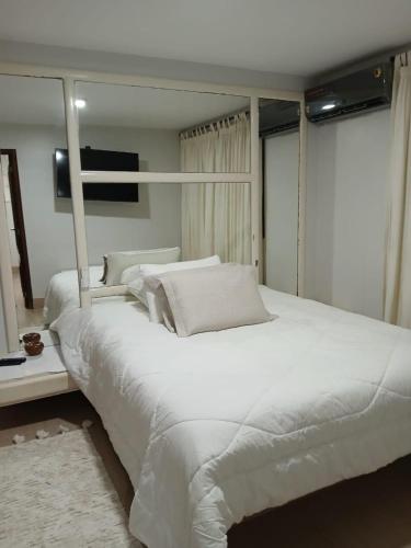 a large white bed in a room with a mirror at Excelente Casa para 10 pessoas proximo ao Shopping Flamboyant- Serra Dourada-Autódromo in Goiânia