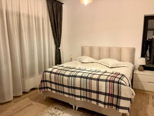 a bedroom with a bed with a plaid blanket and a window at Del House in Zărneşti