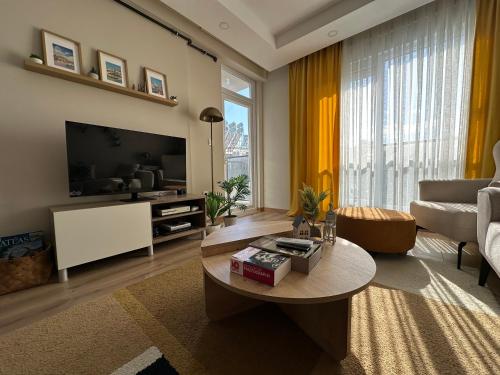a living room with a tv and a couch and a table at Chic 2BR City Center Flat in Antalya