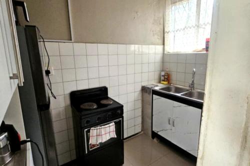 Una pequeña cocina con estufa y fregadero. en Bacarra CBD, en Harare
