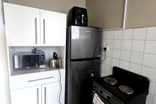 Una cocina con un refrigerador negro y una estufa. en Bacarra CBD, en Harare