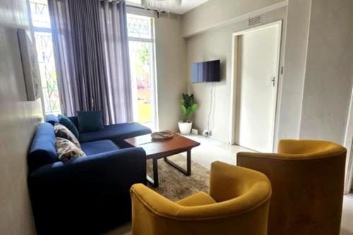 Una sala de estar con un sofá azul y dos sillas. en Bacarra CBD, en Harare