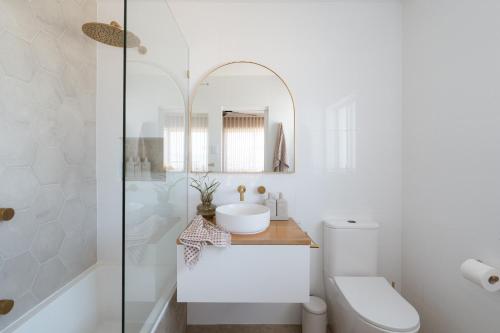 a white bathroom with a sink and a mirror at The Nook in Aldinga Beach